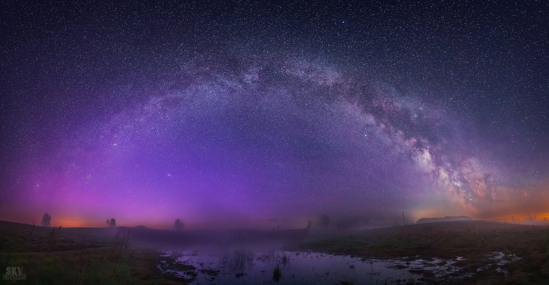Paukščių tako panorama virš rūku apgaubtų laukų ir vandens balos paryčiais